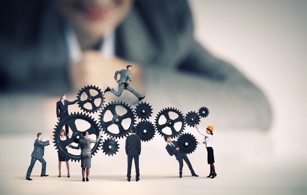 Businesswoman looking at team of businesspeople in miniature